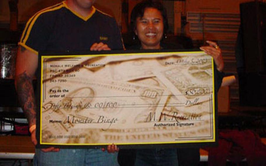 Charles Dry and Pramchit Martinson accept their ceremonial check for $50,000 at Yokosuka's Morale Welfare and Recreation Monster Bingo Game, Sunday Oct. 5, 2003. More than $110,000 in cash prizes were awarded Sunday, at Yokosuka Naval Base's Thew Gym. Dry and Martinson will each get $25,000 before taxes.