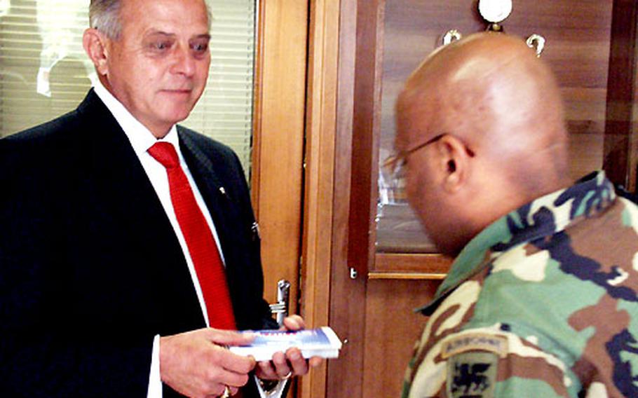 Ed Banas, the national commander in chief of the Veterans of Foreign Wars, passes out free phone cards Friday at the South of the Alps dining facility at Caserma Ederle in Vicenza, Italy.