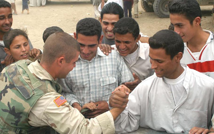 Spc. Sean Raby of the 1st Battalion, 152nd Infantry, arm wrestles an Iraqi man from the village of al-Jawdia on the hood of a humvee as members of the 161st Area Support Medical Battalion provided medical support to villagers in the nearby clinic. Raby lost the match, but chalked it up to improper technique on the Iraqi's part.
