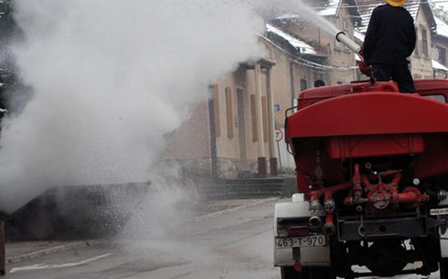 A firefighter puts out a fire in a trash bin during Saturday's joint exercise of fire departments from nine Bosnian towns.