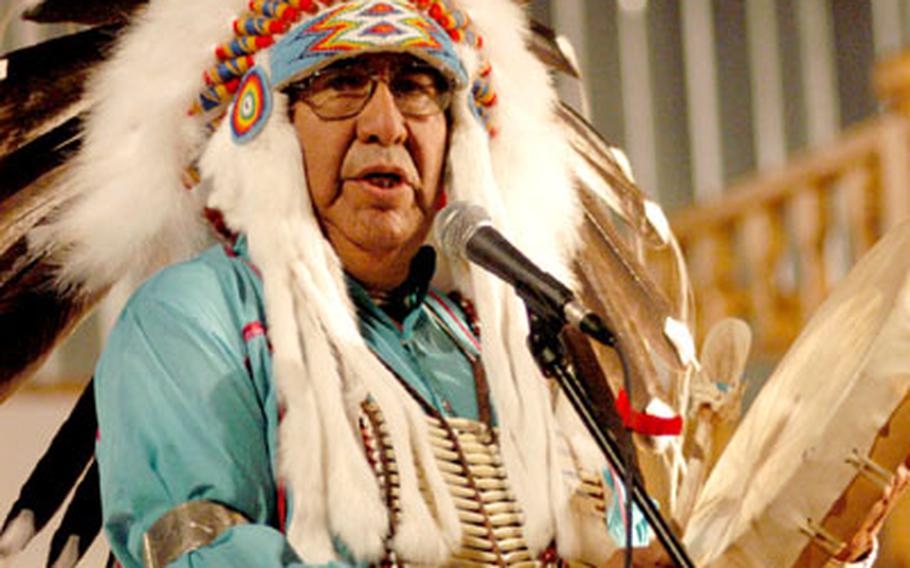 Ralph Zotigh, the leader of Full Circle Regalia Dance Company, sings and plays drums for a military audience at Camp McGovern.