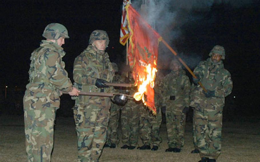 Cpl. Jeremy Bradley, Maj. Ivan Beckman, and Sgt. Major Thomas Gibbons (left to right), all from the 2nd Engineer Battalion, 2nd Infantry Division, burn the colors Sunday during an annual ceremony to commemorate a Korean War battle in which surrounded American troops destroyed the flags instead of letting them fall into enemy hands.