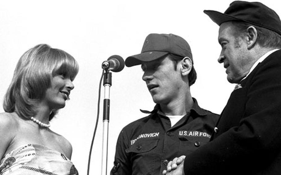 Airman Freddie Bogonovich of the 475th Supply Squadron joins Bob Hope and Miss World, Belinda Green, onstage at Yokota.