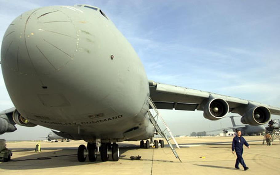 An airman walks on the ramp at Morón Air Base in Spain next to an Air Force C-5 cargo plane.