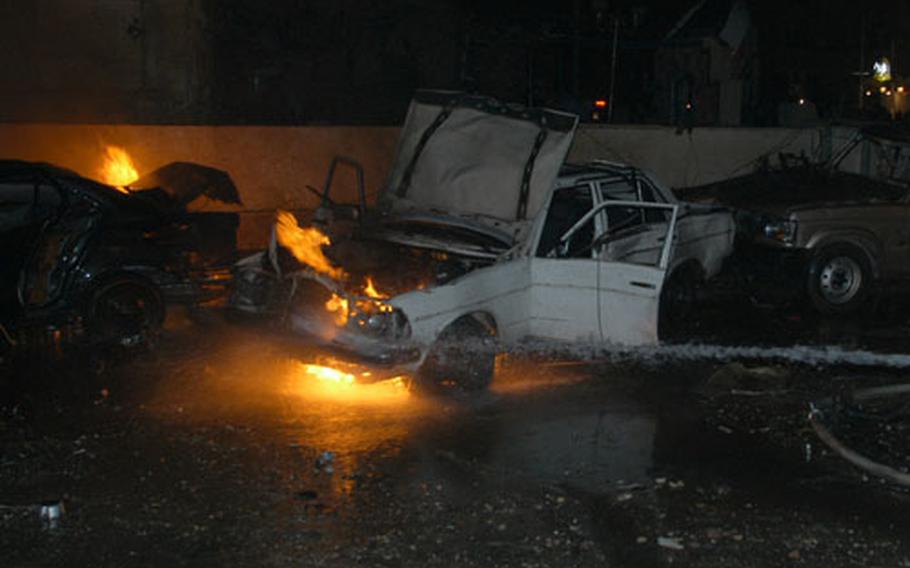 Cars burn outside a restaurant in Baghdad, Iraq, on New Year's Eve after a powerful car bomb went off, killing five patrons and injuring more than 30 other people. The blast brought troops of 1st Armored Division to the scene.