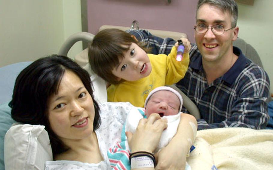 Mami Dolberry proudly holds her son Mikoto, the first baby born at an overseas U.S. military base in the Pacific in 2004, in her room and Naval Hospital Yokosuka on Friday. Father Mitchell Dolberry, of Fleet Technical Support Center, and Morgan, the baby’s 2-year-old brother, are also pictured.
