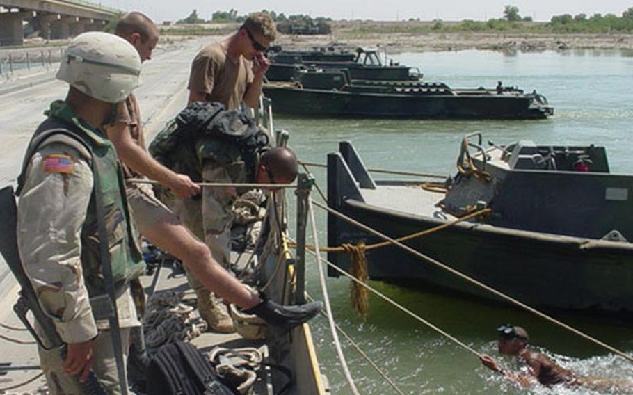 Members of the team assist Sgt. Benjamin Park, a diver searching for a machine gun in the Tigris River.