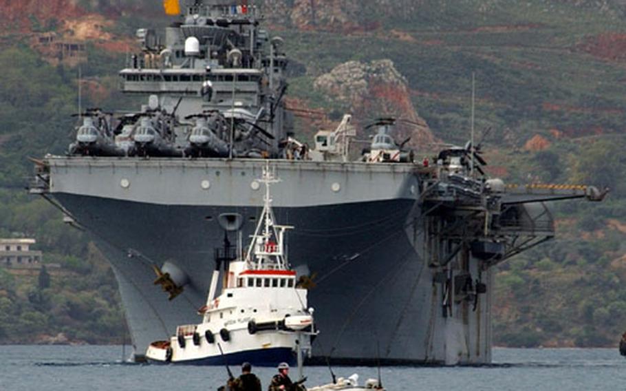 The USS Wasp pulls into Souda Bay, Crete, in March 2002 as members of the base's port security unit sail nearby. Souda Bay was recently awarded the Secretary of the Navy's Meritorious Unit Commendation for its role in operations between Sept. 11, 2001, and Sept. 30, 2002.