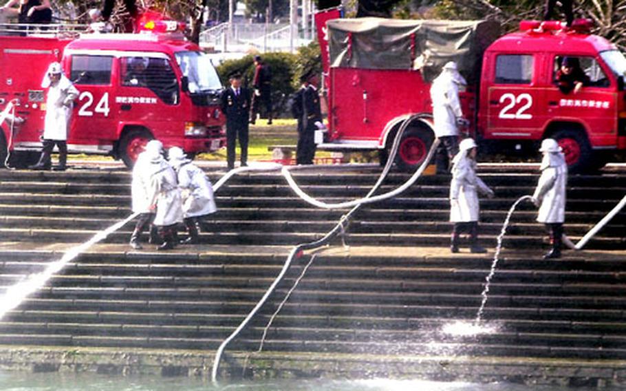 Personnel from a Sasebo city fire detachment hold a hose nozzle steady as a powerful flow of water comes to an end in the canal.