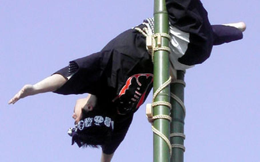 A member of the Edo Shobo Kinenkai (Edo Firemanship Preservation Association) displays his skill atop a ladder in the New Year Firemen's Review on Tuesday at Ariake, Tokyo.