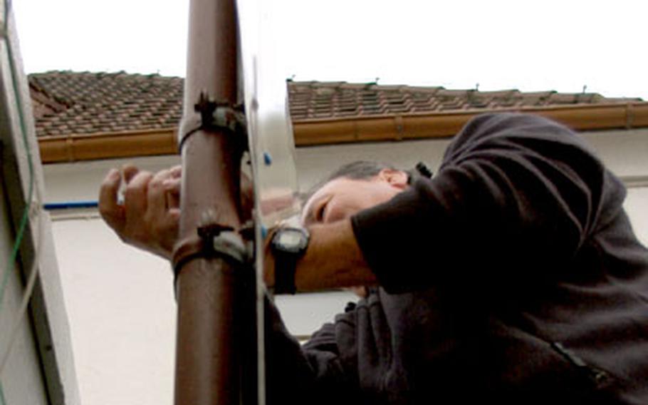 Louis Diaz, a contractor from Science Applications International Corp., installs a cable that will feed information from the guard shack to the central database at Fahlenberg, Germany.