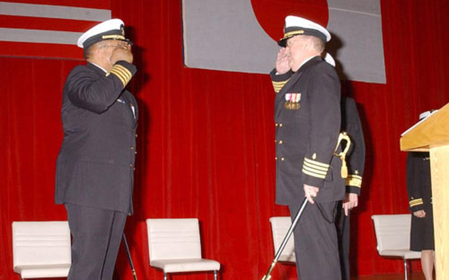 Rear admiral-select Capt. Adam Robinson, left, exchanges salutes with Capt. Charles Taylor, the new Naval Hospital Yokosuka commander during a change of command ceremony Friday at Fleet Theater.