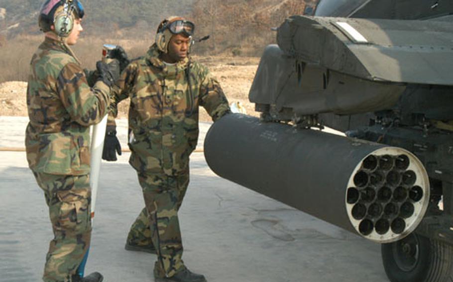 Ground crew members from the 1st Battalion, 2nd Aviation Regiment load Hydra rockets into an Apache before gunnery practice at Rodriguez Range this week.