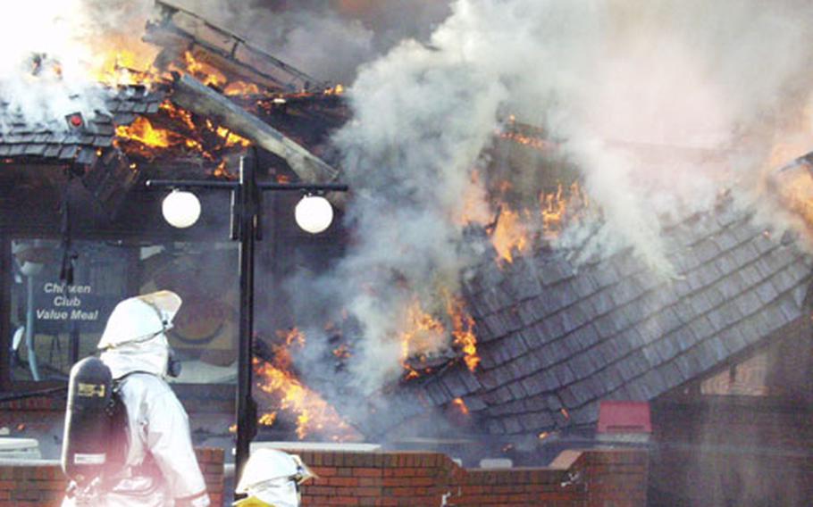 Two members of the Aviano Air Base, Italy, fire department look on as part of the Burger King ceiling collapses Monday.