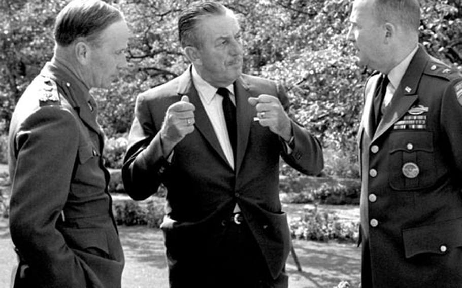 In September, 1963, Brig. R. H. Whitworth, British brigade commander in Berlin, left, and Brig. Gen Frederick 0. Hartel, commanding general of Berlin U.S. Brigade, listen to Walt Disney explain the movie he is going to make in West Germany.