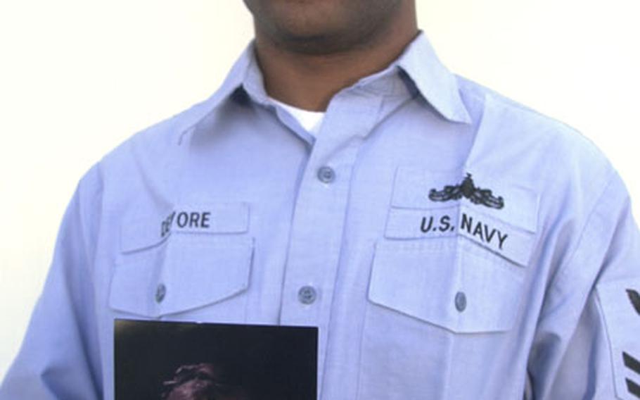 Petty Officer 2nd Class Kemo Devore, who works in the Port Operations department at Naval Station Rota, Spain, holds a photo of his sister, Kimberly Devore. He donated a kidney in August to his sister in the United States. Both have recovered from the surgery and are doing well.