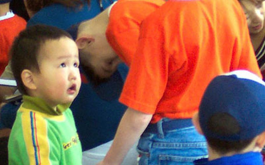 A Cub Scout from Pack 34 plays with a child Saturday at the Aikeikai Orphanage in Machida, Japan. About 35 scouts and their parents from Camp Zama donated 1,000 pounds of baby and children’s items.