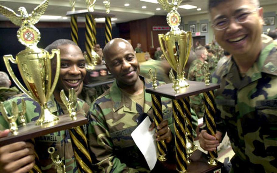 Capt. Anterrio Gainwell, left, Master Sgt. Jerome Sutton, center, and Staff Sgt. Daniel Soh from the 34th Support Group Motor Pool hoist their trophies for maintenance awards Tuesday.