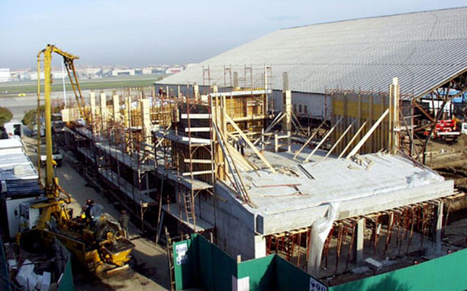 Workers lay cement at Naval Support Activity Naples’s Hangar 406 on Tuesday. The hangar in Italy is going through a major renovation, and is expected to be completed March 2005.
