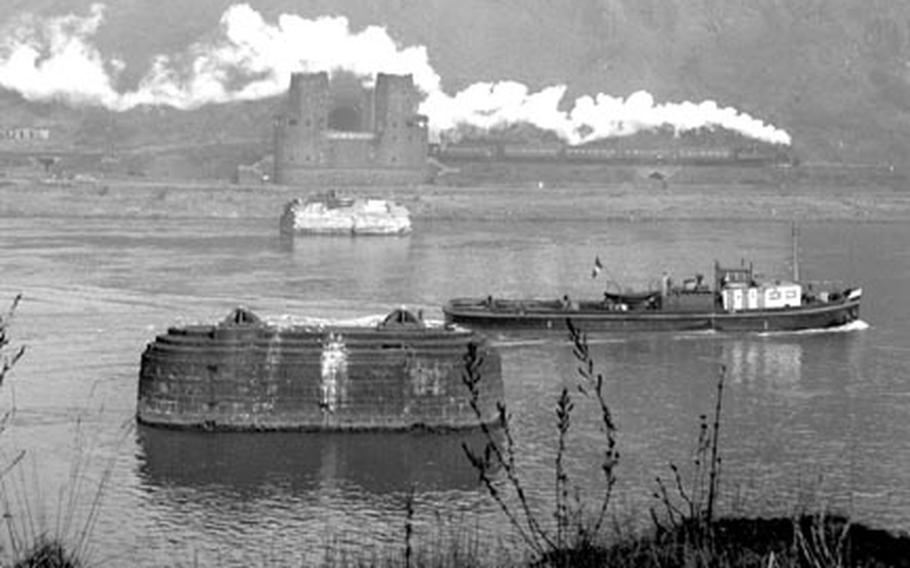A boat moves down the Rhine, past the remnants of the Remagen bridge.