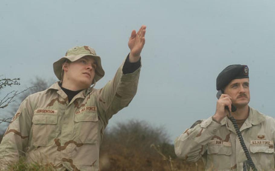 Airman 1st Class Will Jorgenson points toward an F-15E Strike Eagle as Master Sgt. Jim Burt talks to the pilot to direct close air support in an exercise near RAF Lakenheath, England, on Thursday.