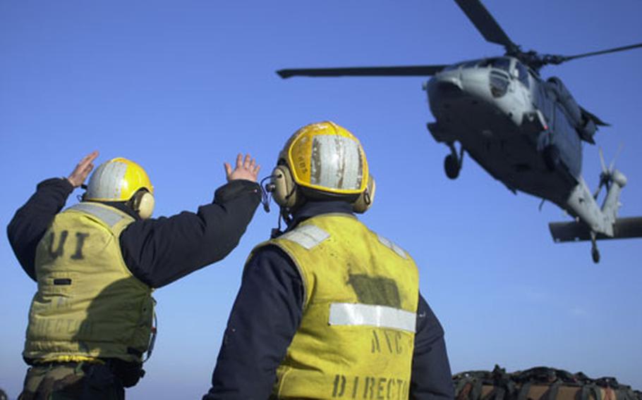 Navy aircraft directors guide a helicopter during a vertical replenishment operation aboard the amphibious assault ship USS Bataan on Thursday in the Mediterranean Sea.