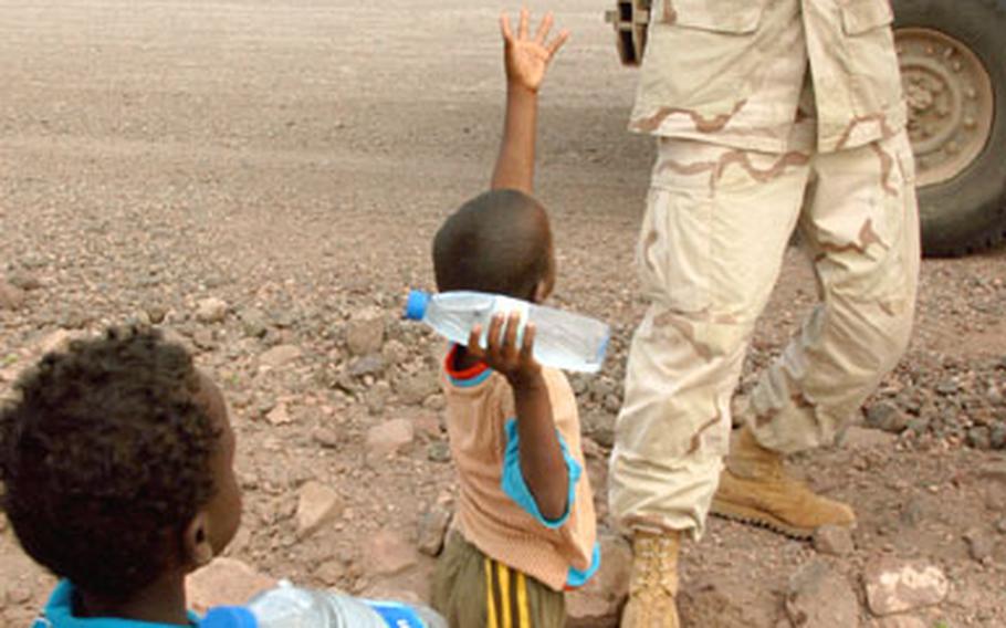 Staff Sgt. Arthur Dodds, 35, an Army reservist from Hopedale, Ohio, hands out water to Djiboutian children on a road that he helped repair near Djibouti City.