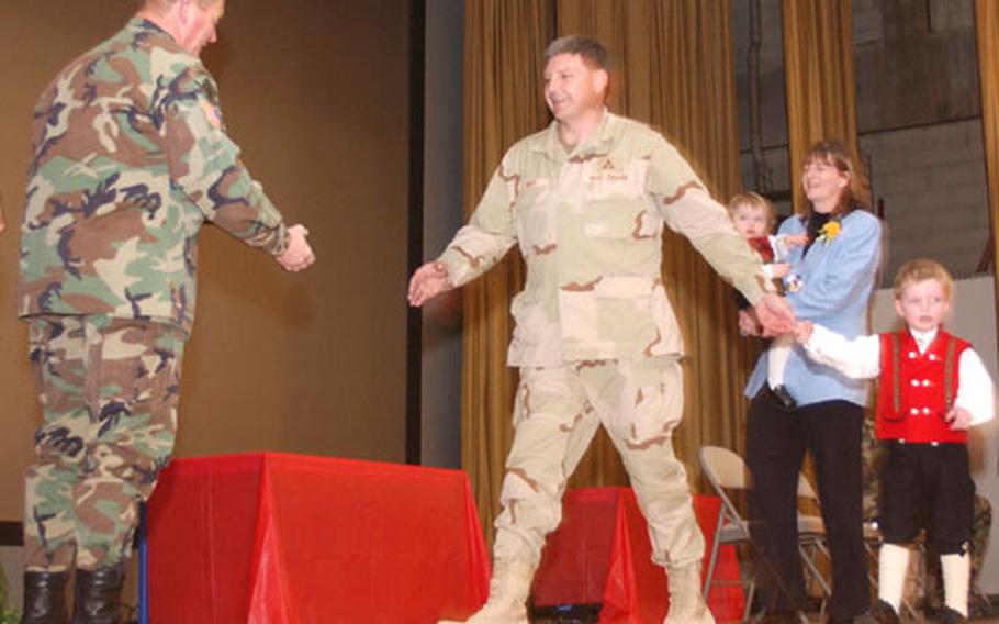 Lt. Gen. Robert B. Flowers, commanding general of the U.S. Army Corps of Engineers, left, congratulates Ron Mott and his family for his service in Iraq during a ceremony Monday in Wiesbaden, Germany.