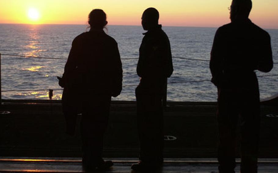 Sailors enjoy a sunset earlier this month from the hangar bay of the USS Bataan. The amphibious assault ship is on its way to the Persian Gulf to supply Marines as part of the largest rotation of U.S. forces since World War II.