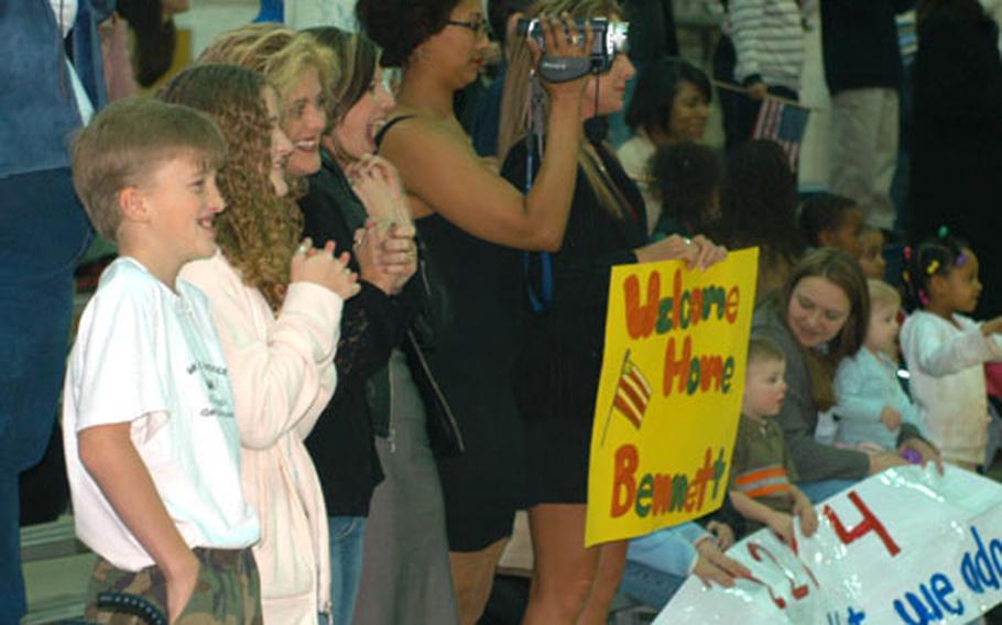 Families react Wednesday to their loved ones from the 5th Battalion, 158th Aviation Regiment, marching into the hangar Wednesday after a one-year deployment to Iraq. A delay of several hours was forgotten when the hangar doors opened and the troops marched in to cheers and whistles from the crowd.