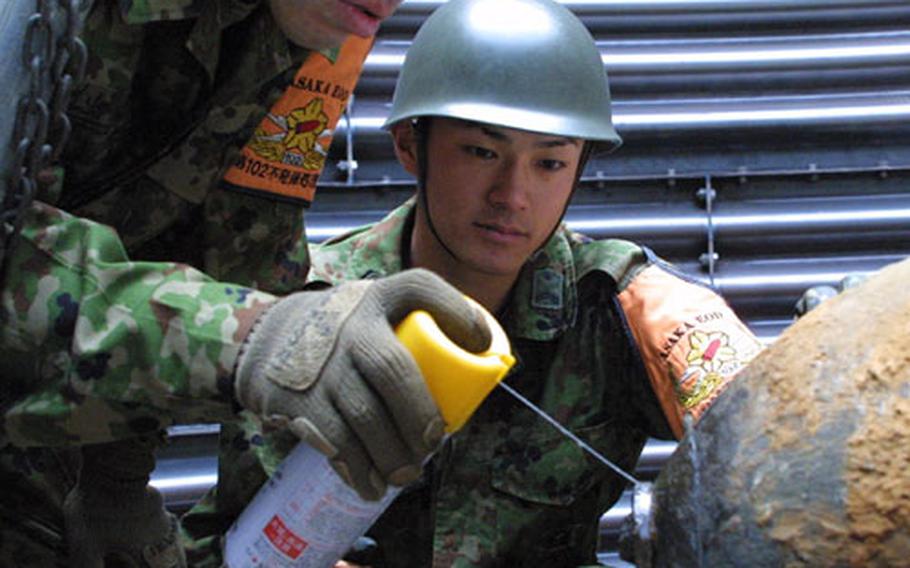 Explosive ordnance disposal members from Japan's Camp Asaka work on a World War II-era U.S. bomb Thursday discovered in Numazu City late last month.