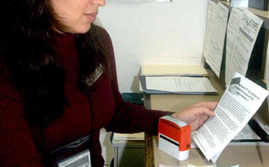 Betzy Centeno, the lead sales store checker at the Rhein-Main Air Base commissary, learns how to properly stamp checks for the new returned check process beginning this month.