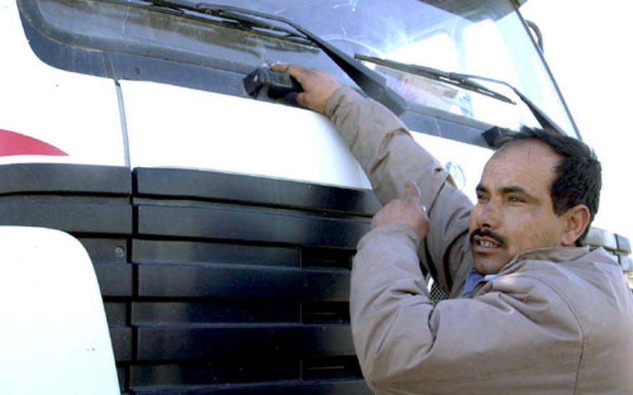 Iraqi truck driver Qasim Al-Janabi shows his cracked windshield, caused by someone hurling a rock. Al-Janabi, who delivers concrete barriers that fortify U.S. military compounds around Baghdad, said Iraqis also have shot at his vehicle because he is working for Americans.