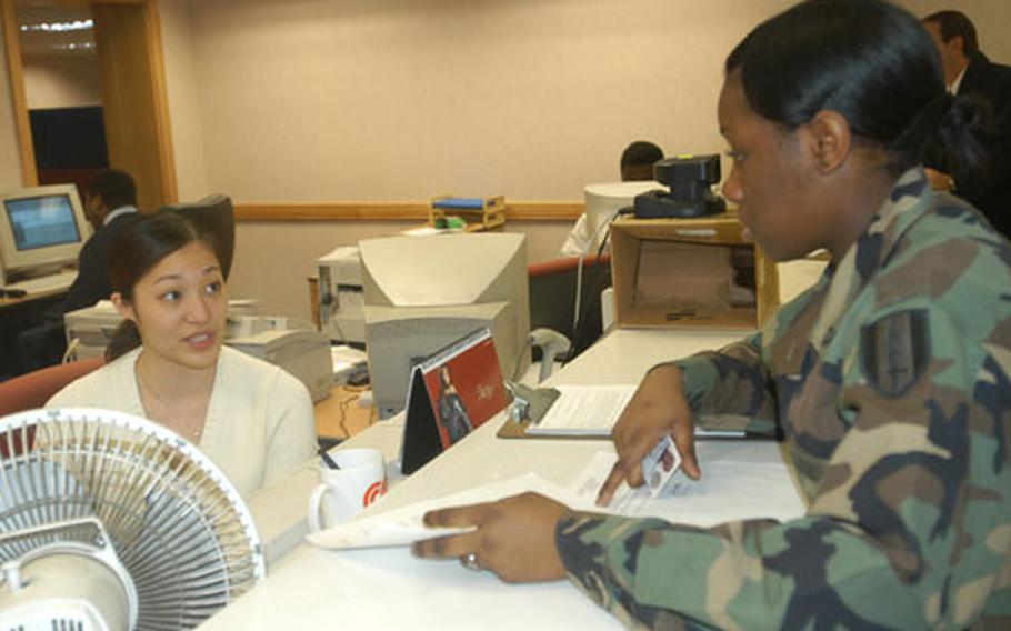 Hellen Kim, a Common Access Card issuer, talks with Pfc. Kemi Warhop, who was getting her ID card replaced because of a name change Wednesday.