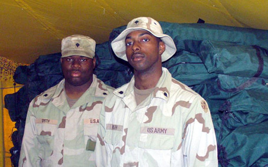 Spc. Shaun Smith, left, and Spc. Terence Adolph, supply clerks at with the Georgia National Guard's 277th Maintenance Company, stand before a floor-to-ceiling stack of about 500 broken cots turned in by troops as Camp New York, Kuwait. The cots, provided by a contractor in Kuwait, have not stood up to the rigors of Army use. Smith and Adolph said they are being replaced by standard Army-issue cots.