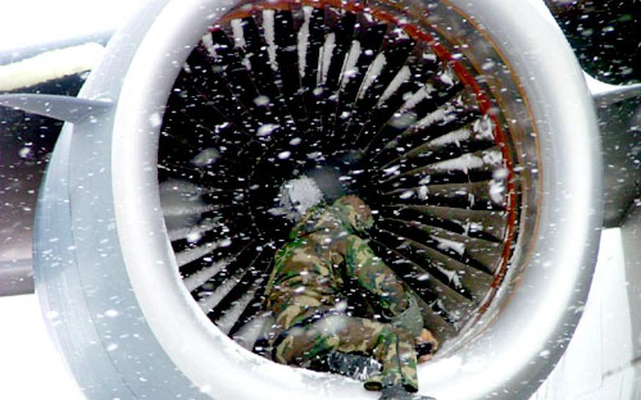 Senior Airman Nathan Hill of the 726th Air Mobility Squadron at Rhein-Main Air Base, Germany, checks the fan blades on a jet engine of a C-17 cargo jet during Wednesday’s snowstorm.