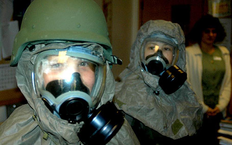 Sixth-graders Elizabether Bingham, left, and Ryan Martin wear chemical suits Monday during a mock deployment processing at Lakenheath Middle School, RAF Feltwell, England.