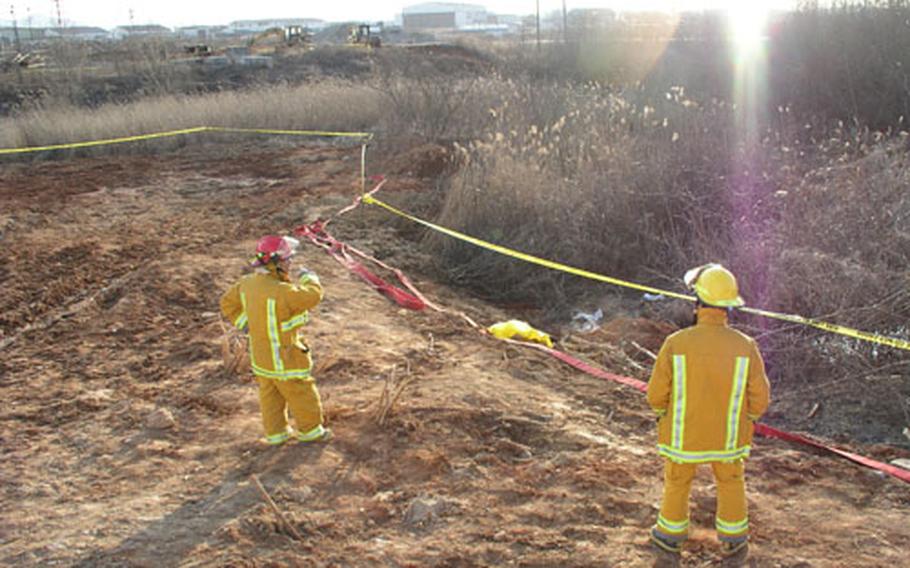 At Camp Humphreys, South Korea, firefighters stand near the site of a spill of about 33,000 gallons of fuel oil after a pipe broke Friday morning.