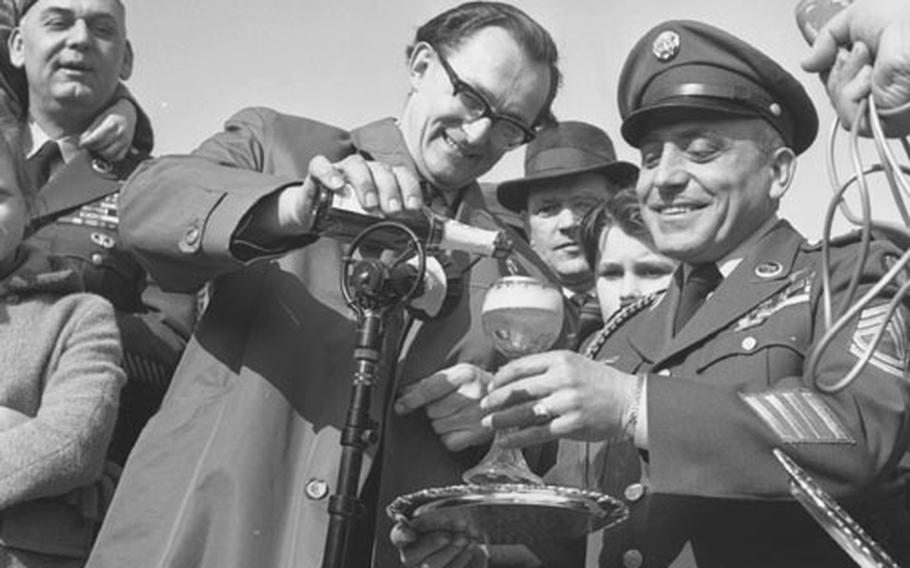 At a reunion 17 years after the battle for the bridge at Remagen, ex-German army sergeant Gerhard Rothe pours a drink of cognac for U.S. Army Sfc. Joseph A. DeLisio.