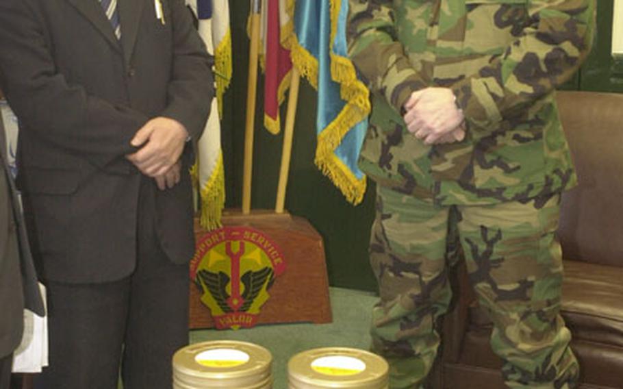 34th Support Group commander Col. Timothy McNulty, right, accepts a stack of film prints of the South Korean national anthem from Choe Young-kun, Gyeonggi Province budget and planning director.