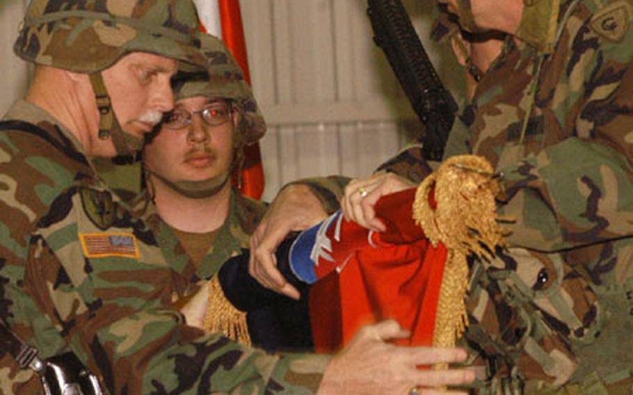 Brig. Gen. Timothy Wright, left, and Command Sgt. Maj. Thomas Severe, unroll the flag of the 38th Infantry Division of the Indiana National Guard at a transfer of authority ceremony Wednesday at Eagle Base, Bosnia and Herzegovina.
