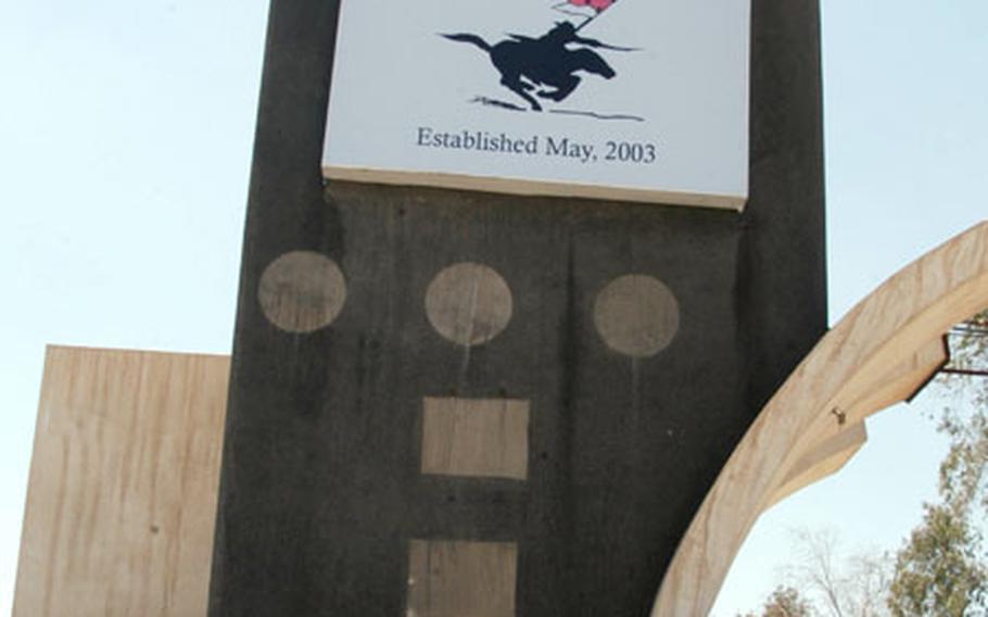 Less than an hour after the official renaming ceremony, a crane hoists a new sign at the gate of the former Camp Muleskinner in Baghdad. The camp was renamed in honor of Pfc. Rey D. Cuervo, who was killed in action in Baghdad on Dec. 28, 2003.