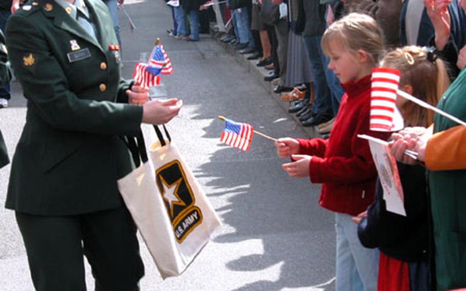 Spc. Courtney Quinn of the 105th Military Intelligence Battalion hands out flags Sunday during the Farewell Fest parade in Bad Aibling, Germany. The U.S. Army base there is closing after more than 50 years of American operation.