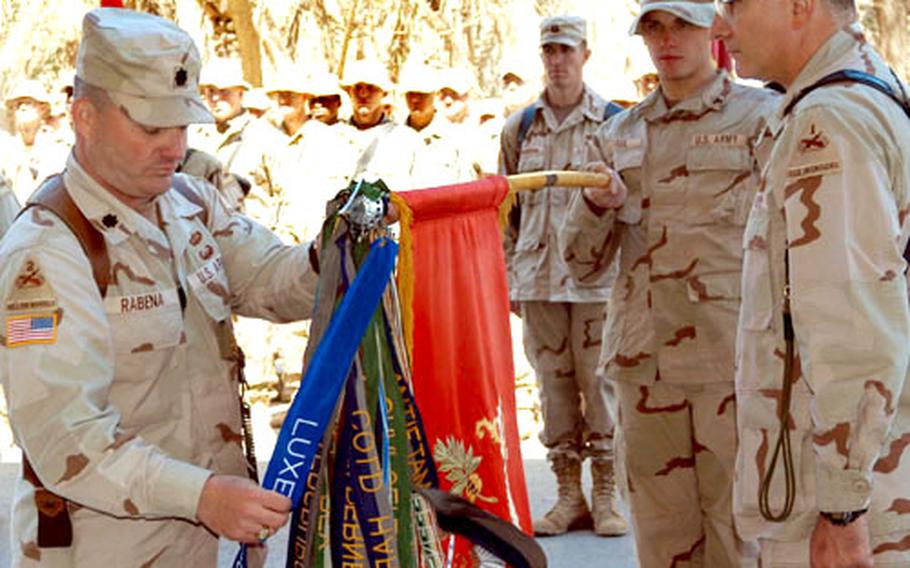 Lt. Col. William Rabena, commander of 2nd Battalion, 3rd Field Artillery Regiment, 1st Armored Division out of Giessen, Germany, straightens the Luxumbourg battle streamer after it was attached to the battalion's colors by 1st Brigade Combat Team commander Col. Peter Mansoor, right. The honor has been a long time coming, as it was earned by Battery A, 3rd Armored Field Artillery Battalion in Luxembourg on December 16, 1944, during the Battle of the Bulge. The Presidential Unit Citation was signed by then-President George H.W. Bush on June 12, 1991, but it was not until Monday's ceremony in Baghdad, that the 2-3 FA added the streamer. According to Rabena, most of the credit for finally receiving the honors goes to retired Maj. Gen. George Ruhlen, commander of the 3rd Armored Field Artillery Battalion at the time. He is also a former 1st Armored Division Commander.