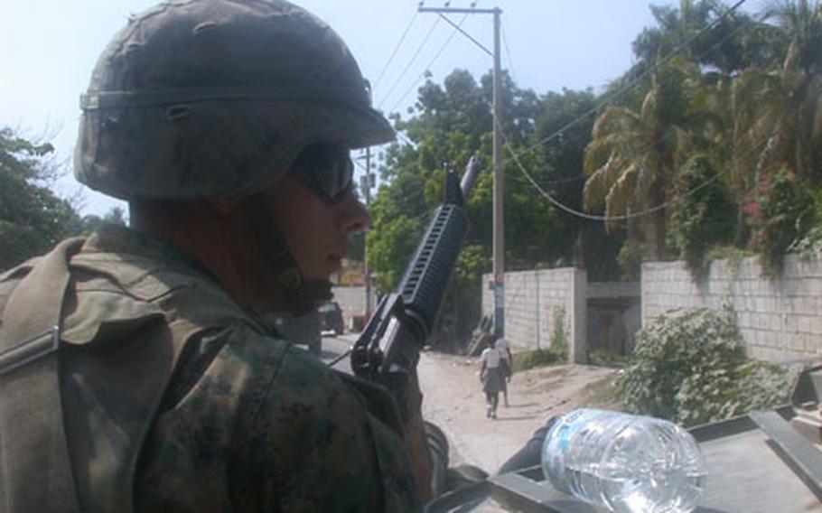 Lance Cpl. Michael Aichner, 23, with Weapons Platoon, Bravo Company, 2nd Light Armored Reconnaissance Battalion scans sidewalks during a Light Armored Reconnaissance patrol Wednesday through neighborhoods in Port au Prince Haiti known to house gang members.