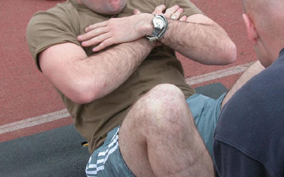 Staff Sgt. Quinton Hunt of Hokah, Minn., and with the 31st Maintenance Squadron, fights to do one last crunch Friday as part of his Air Force fitness test at Aviano Air Base, Italy.