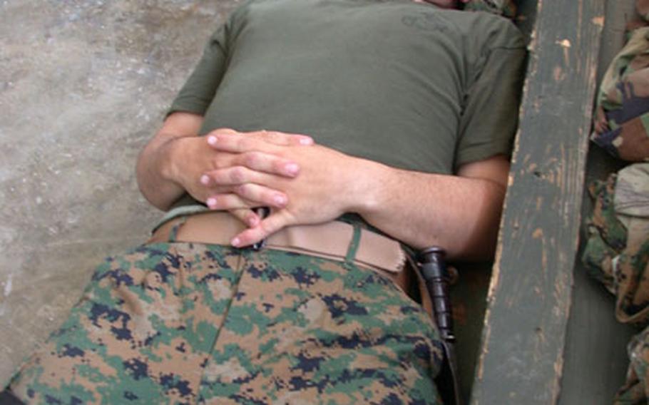 After working for hours and hours reconfiguring computers in the Communications Platoon office Saturday after the Internet system supporting the 3rd Battalion, 8th Marines crashed Friday, Sgt. Mickey Fernandez, 23, finds a bit of respite where he can – on a six-cube embark box.