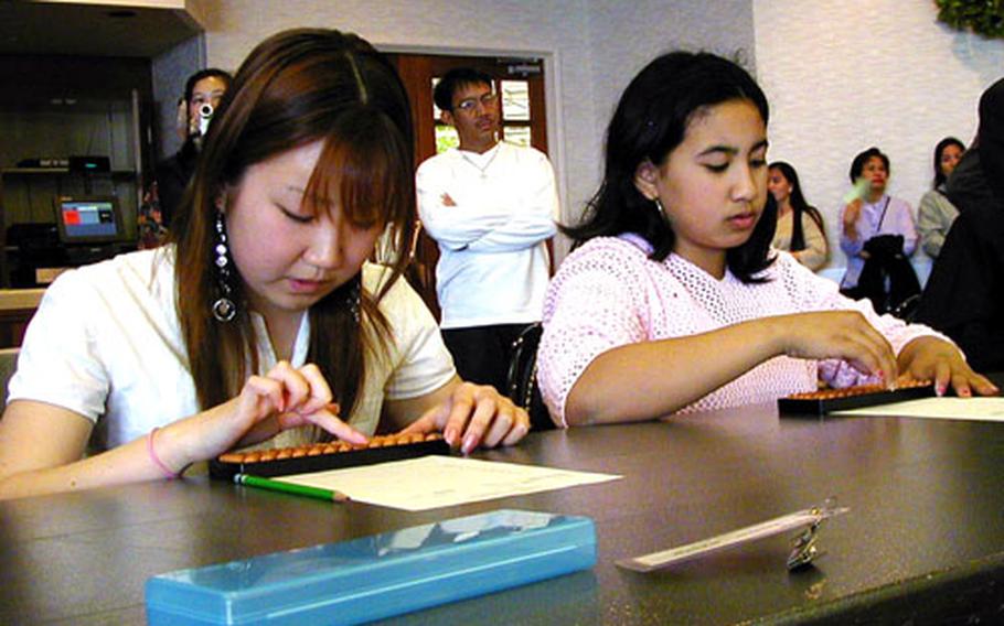 At the Sasebo Naval Base Soroban Taikai Wednesday, Miku Fiala, at left, was the winner among students in the 7th through 9th grades. Justine Lamoglia, 7th grade, also participated among the approximately 40 students in the abacus event.