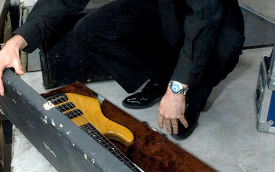 Petty Officer 2nd Class Greg Fritz, supply petty officer for the 6th Fleet band, packs up an electric bass guitar to be given to the Naples American High School band.