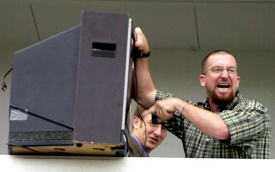 Ernest J. King High School teacher Kevin McGrath prepares to push a television set off a second-story ledge at the Sasebo Naval Base school on Tuesday.